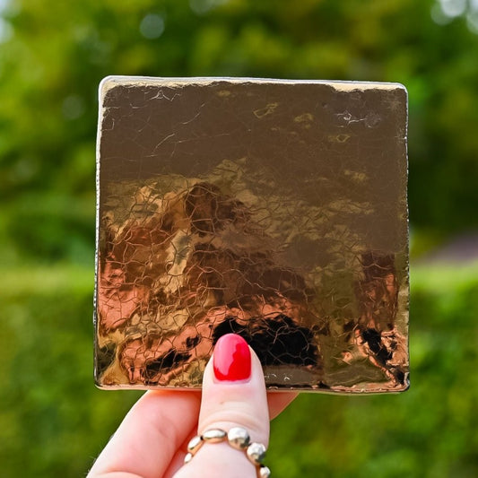 Mooie goud gekleurde tegel in de hand in de lucht. Voor jou personaliseren wij deze met liefde