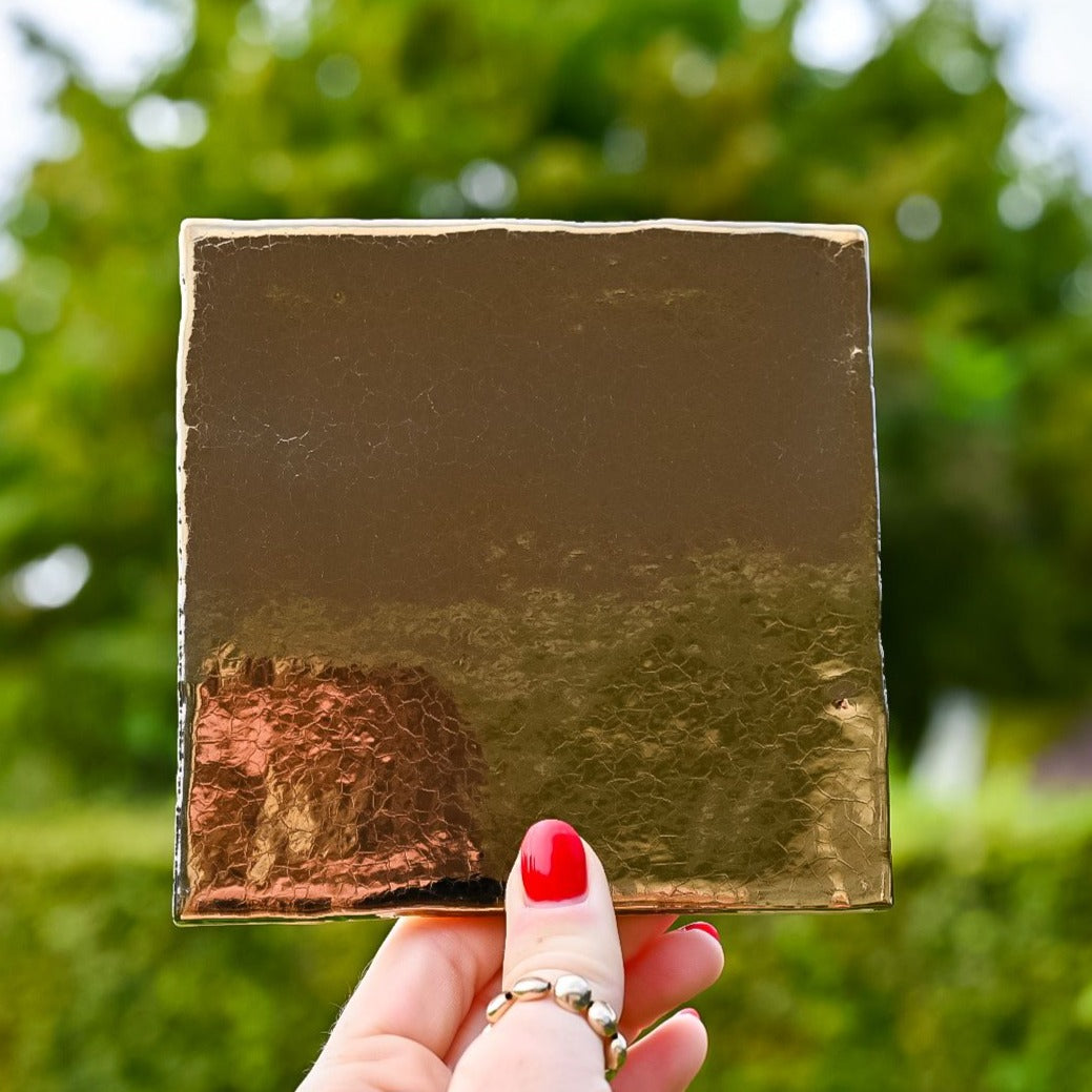 Mooie goud gekleurde tegel in de hand in de lucht. Voor jou personaliseren wij deze met liefde